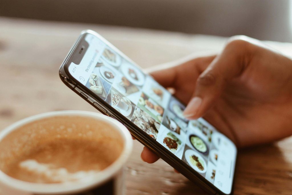 Ruka s mobitelom koja slika šalicu kave
